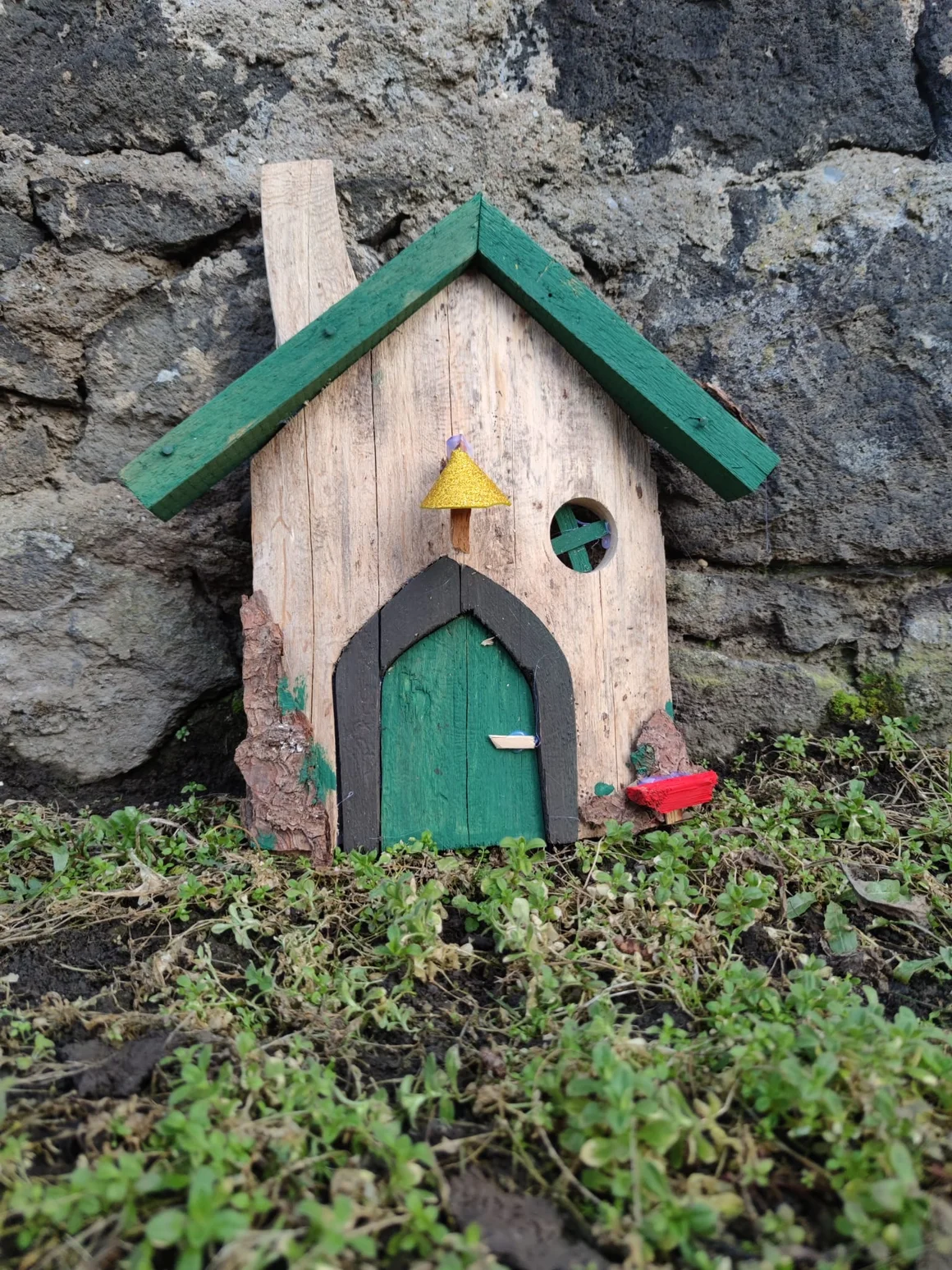 Ein kleines, selbstgebautes Wichtelhaus aus Holz mit grünem Dach.