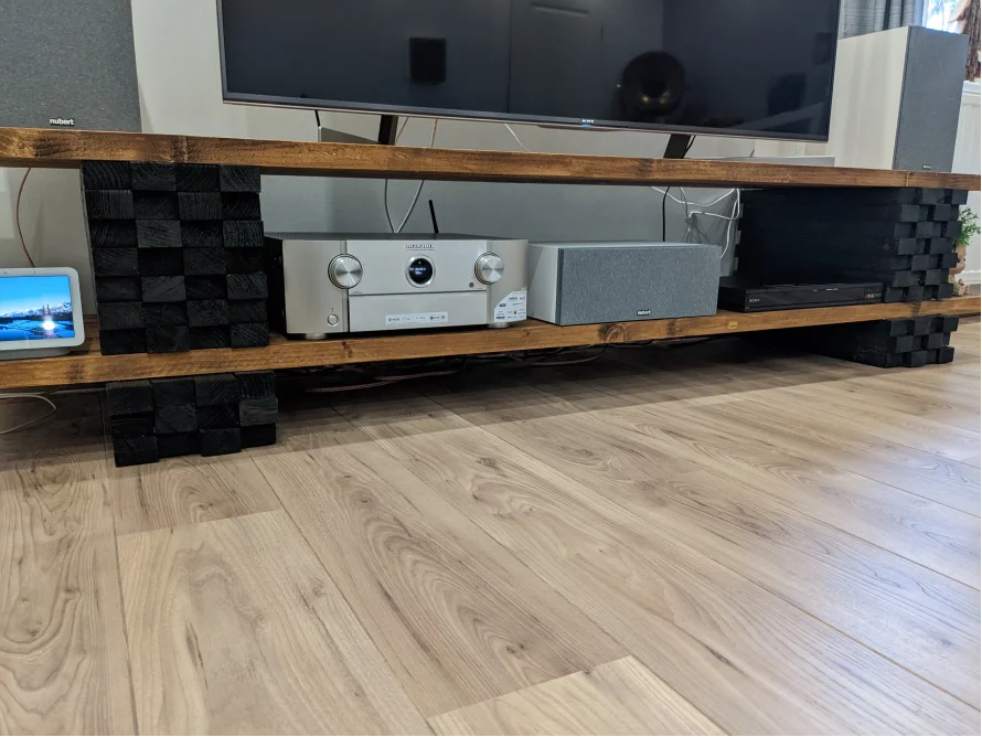 Ein Fernsehtisch aus Holz mit Geräten darauf.