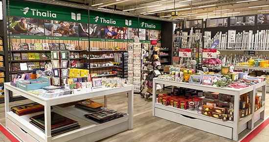 Verkaufsfläche einer Buchhandlung mit Büchern und Geschenkartikeln auf Tischen und in Regalen.