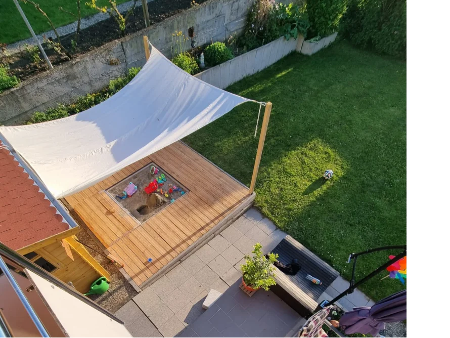 Sandkasten mit Sonnensegel im Garten