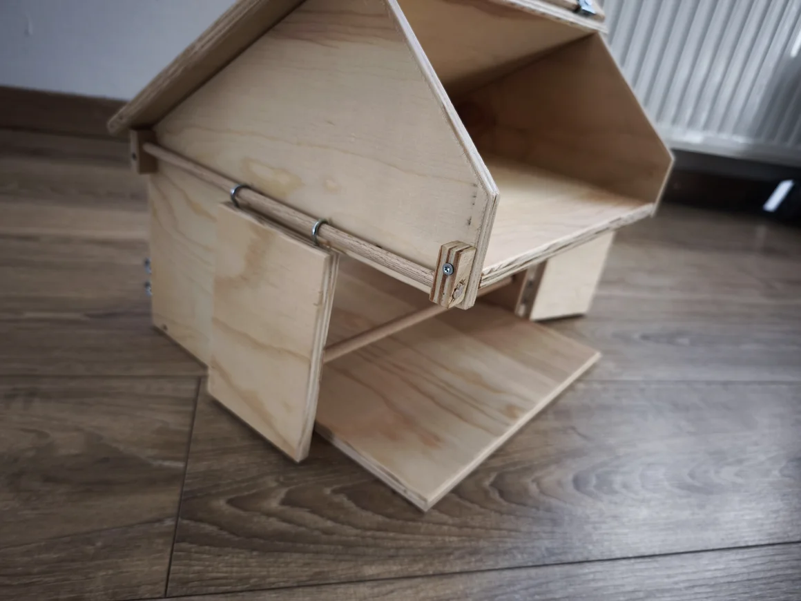 Ein kleines, selbstgebautes Haus aus hellem Holz auf einem Holzboden.