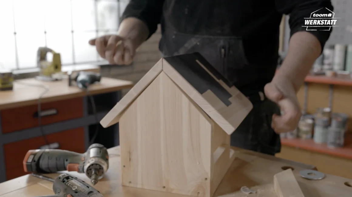 Person baut ein Vogelhaus aus Holz