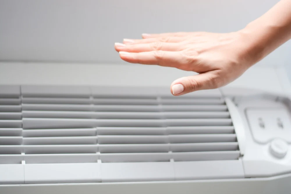 Eine Hand wird über eine Klimaanlage gehalten, um den Luftstrom zu prüfen.