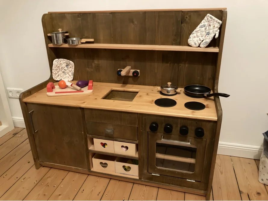 Eine Spielküche aus Holz mit Spielzeug.