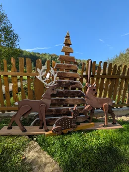 Eine Hirschfamilie aus Holz mit einem Weihnachtsbaum als Gartendekoration.