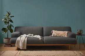 Ein graues Sofa mit Kissen und einer Decke