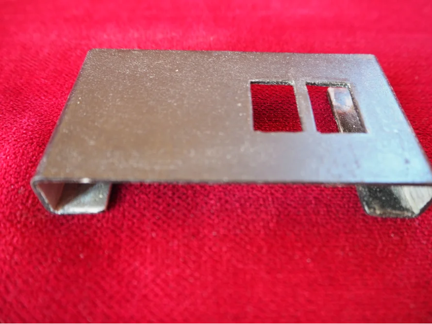 Metallteil mit zwei rechteckigen Aussparungen.