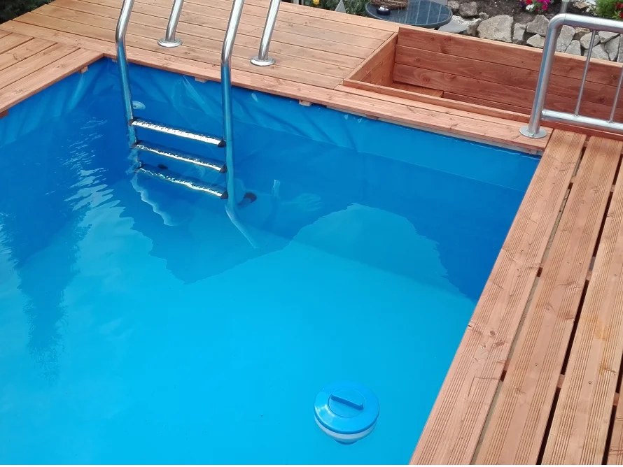 Blauer Pool mit Holzumrandung und Einstieg