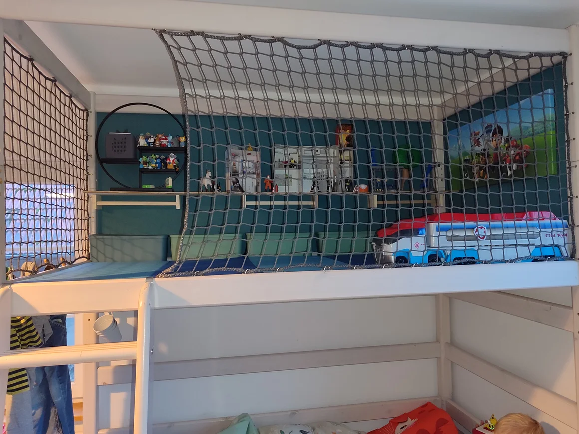 Hochbett mit gesicherter Spielebene und Spielzeug.