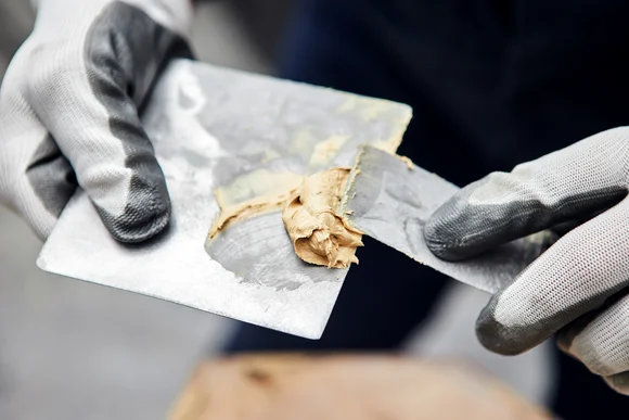 Person trägt Spachtelmasse mit Spachtel auf