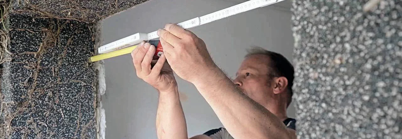 Person misst Türrahmen mit Zollstock aus