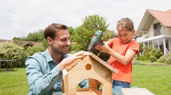 Person und Kind bauen ein Vogelhaus
