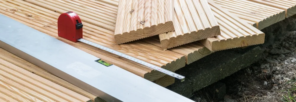Holzlatten, Wasserwaage und Zollstock auf einem Holzboden