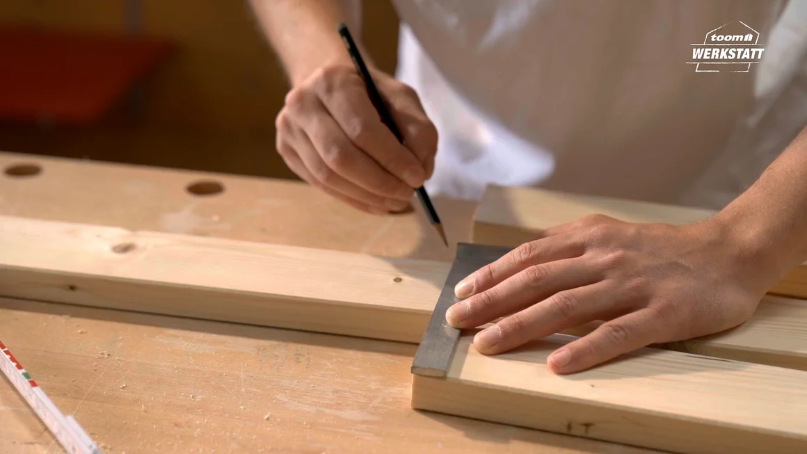 Person zeichnet mit Bleistift auf Holzbrett