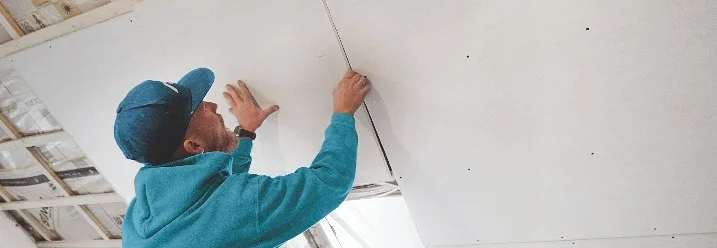 Person bringt Gipskartonplatte an Dachschräge an