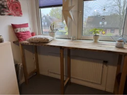 Hoher Tisch aus Holz an Fensterfront