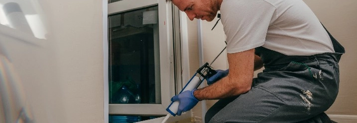 Person kniet und verwendet Dichtmittelpistole