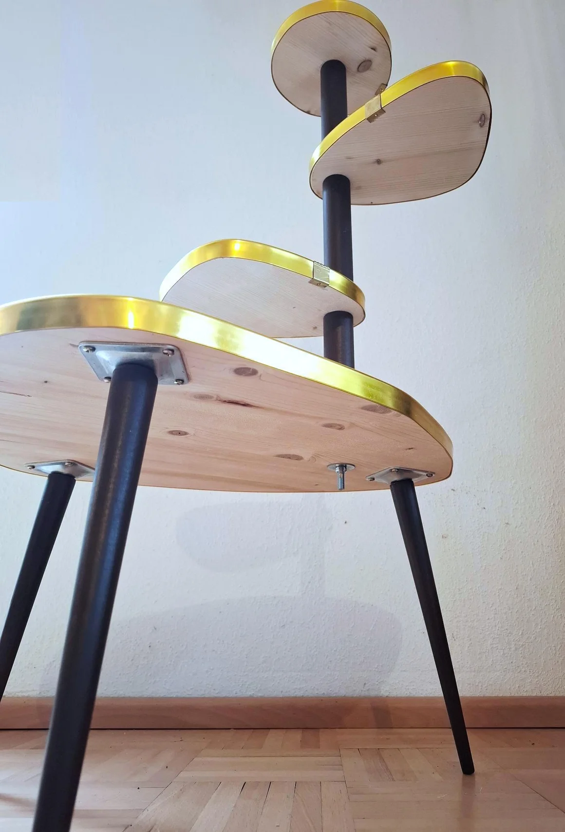 Ein mehrstufiger Blumenhocker aus Holz mit goldenem Rand.