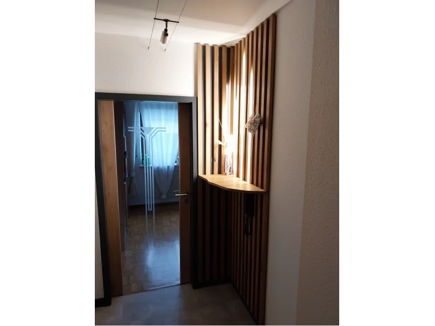Ein beleuchteter Garderobenbereich mit Holzlamellen.