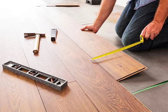 Person verlegt Laminat mit Zollstock