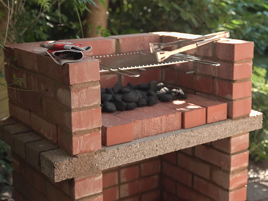 Ein gemauerter Gartengrill mit Grillzange.