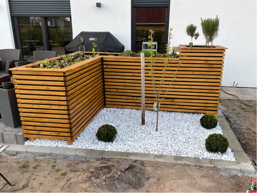 Holzbeet mit weißem Kies