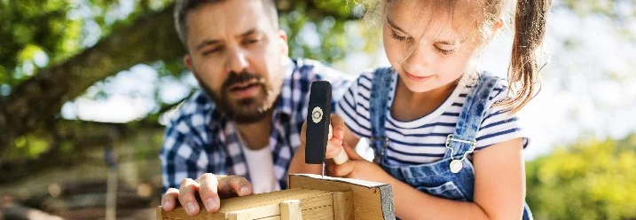 Kind hämmert Nagel in Vogelhaus