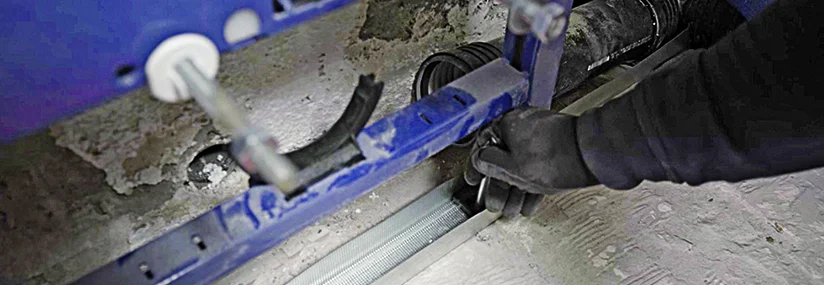 Person montiert eine Metallschiene auf Betonboden.
