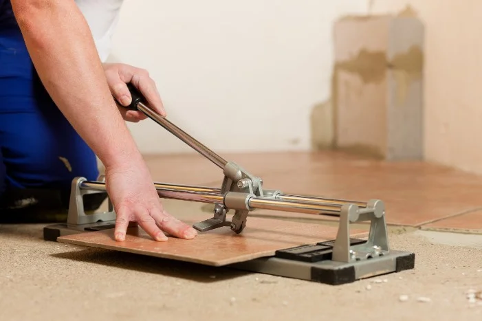 Person schneidet Fliese mit Fliesenschneider