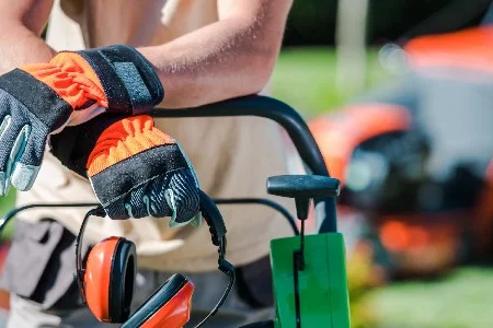 Person mit Arbeitshandschuhen und Gehörschutz
