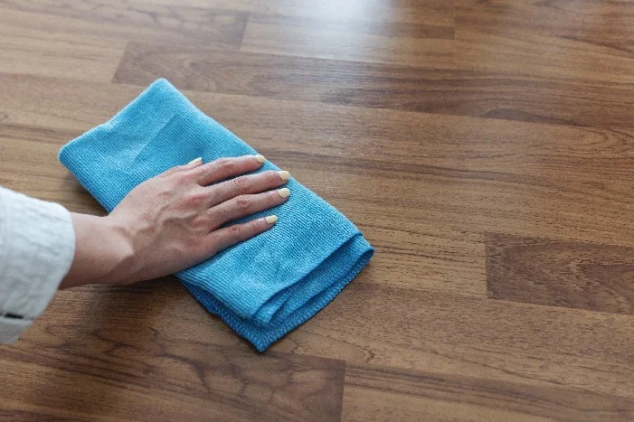 Hand reinigt Holzboden mit Tuch