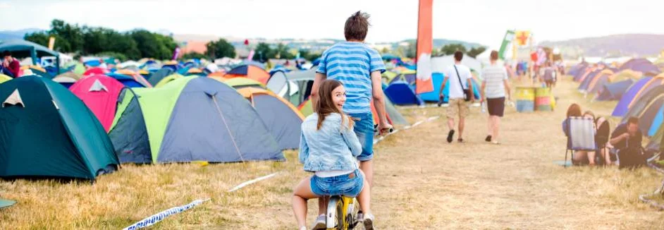 Zwei Personen auf einem Fahrrad auf einem Festivalgelände