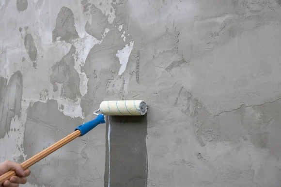 Person grundiert Fassade mit Farbroller