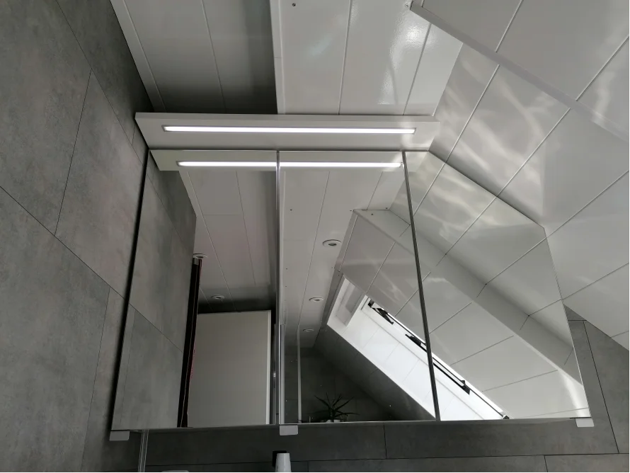 Spiegel in einem Badezimmer mit Dachschräge.