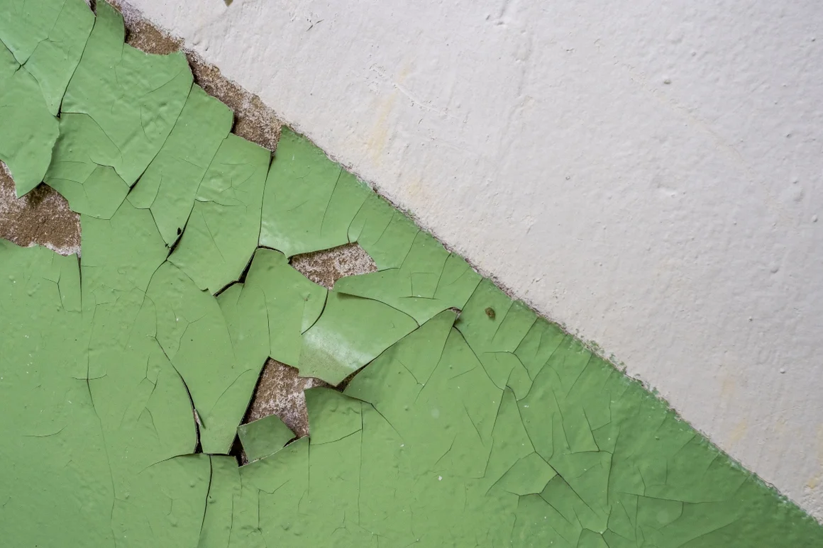 Abblätternde grüne Farbe an einer Wand