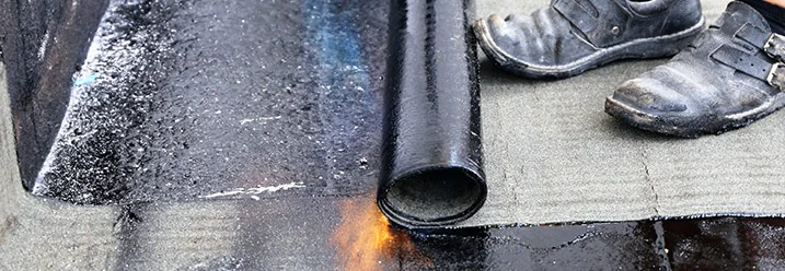 Person bringt Dachpappe mit Gasbrenner an