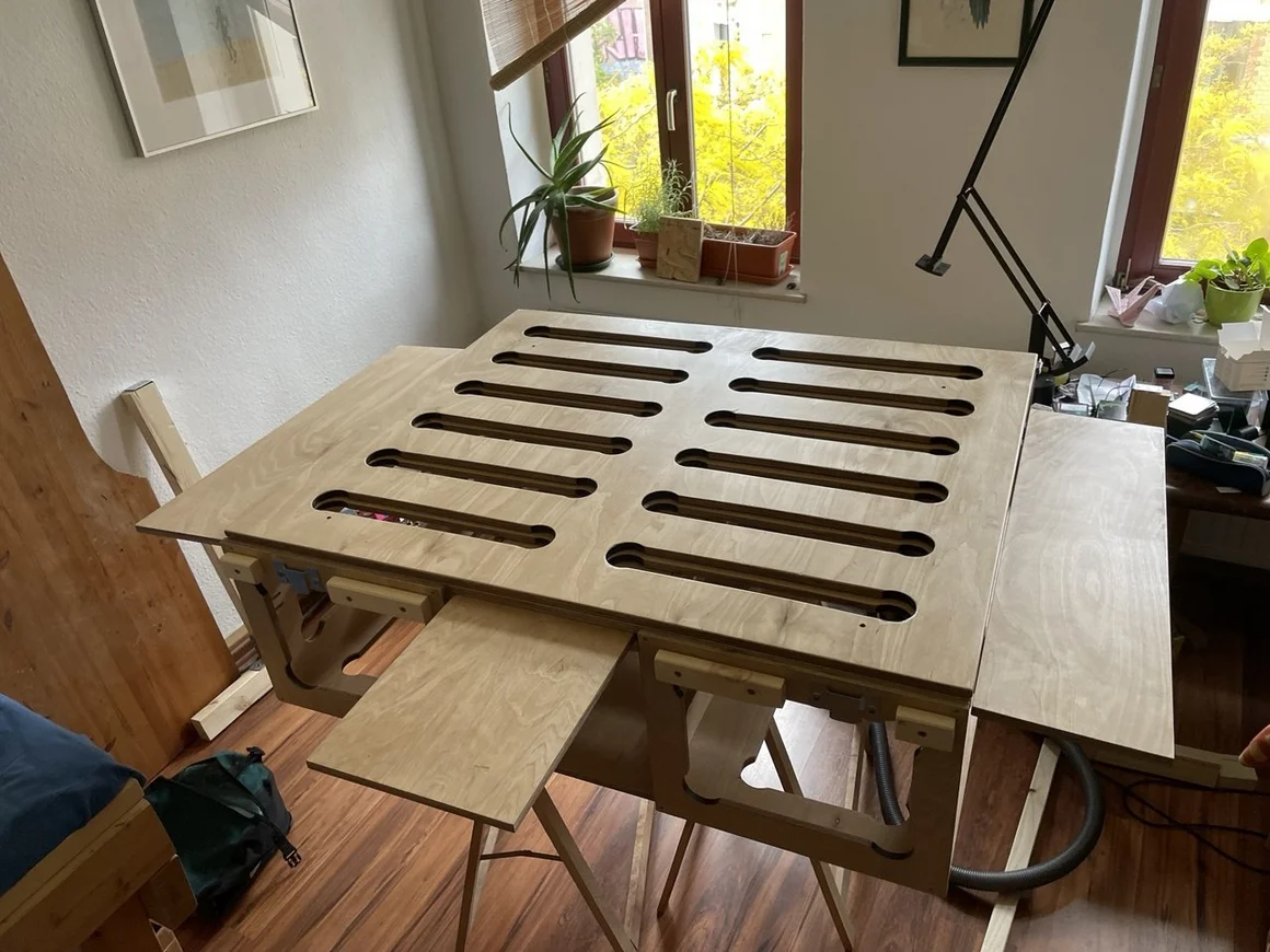 Ein selbstgebautes, ausziehbares Bett aus hellem Holz mit einer Lochrasterplatte.