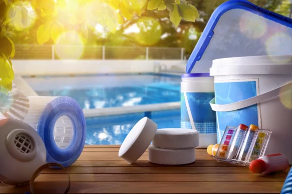 Poolpflegeprodukte auf einem Tisch am Poolrand.