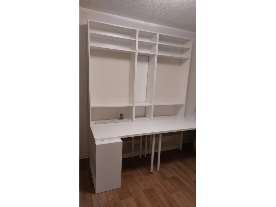 Ein weißer Schreibtisch mit Regalen darüber.
