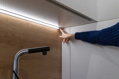 Hand zeigt auf LED-Lichtleiste in Küche