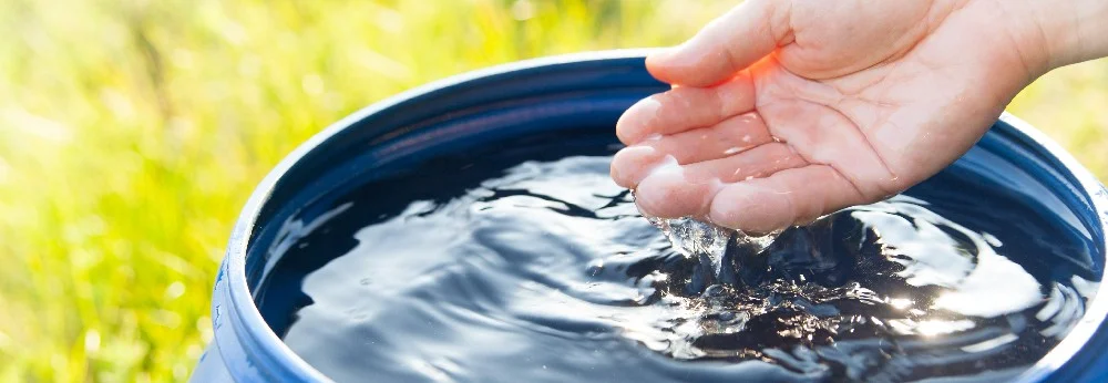 Hand fängt Wasser aus Regentonne
