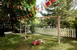 Selbstgebautes Fußballtor mit Werkzeug und Länderflaggen im Garten.