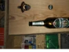 Ein Flaschenöffner und eine leere Glasflasche in einem Holzbrett.