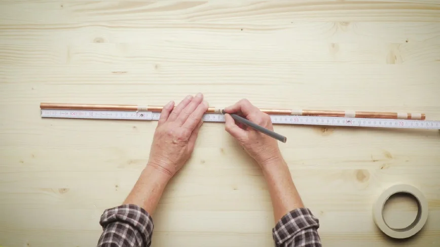 Person markiert Kupferrohr mit Bleistift