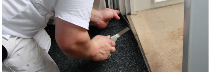 Person schneidet Teppich mit Teppichmesser zu