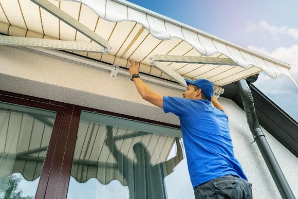 Person montiert Markise an Hauswand