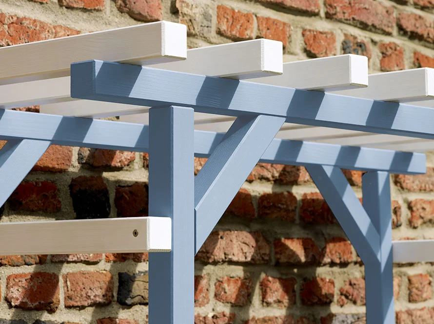 Holzgerüst einer Pergola vor Backsteinwand