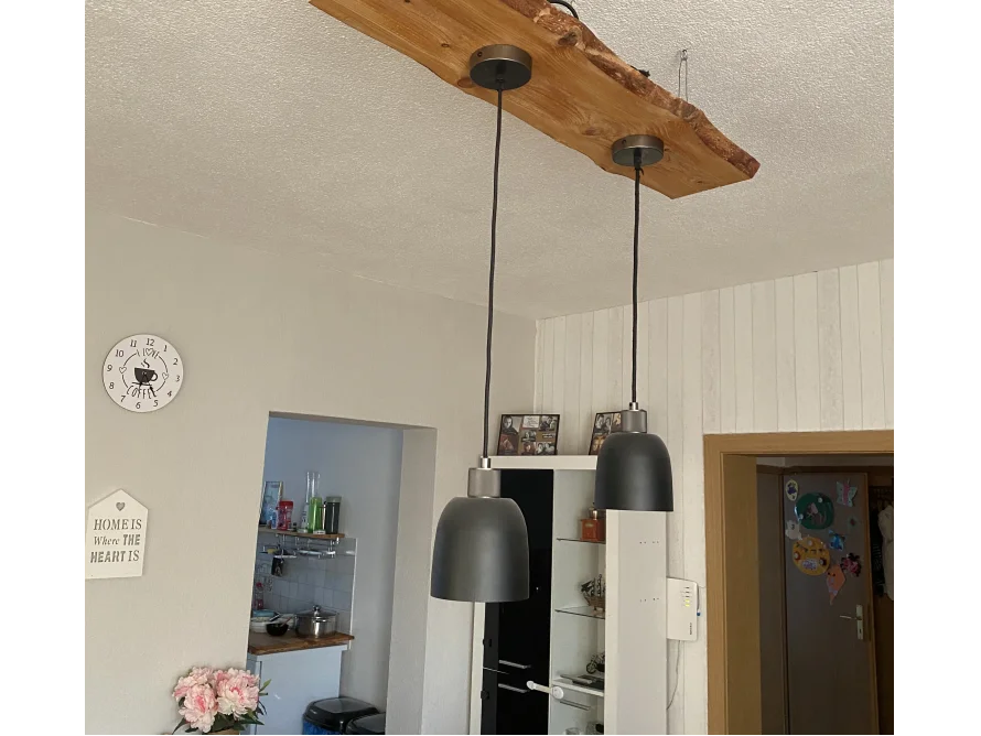 Drei schwarze Hängelampen an Holzbalken