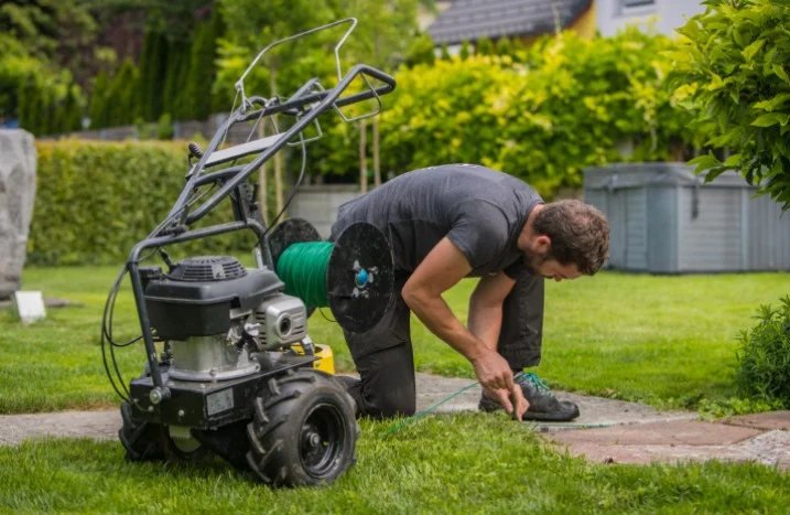 Person verlegt Begrenzungskabel für Mähroboter