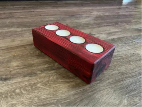 Roter Holzblock mit vier Kerben für Teelichter